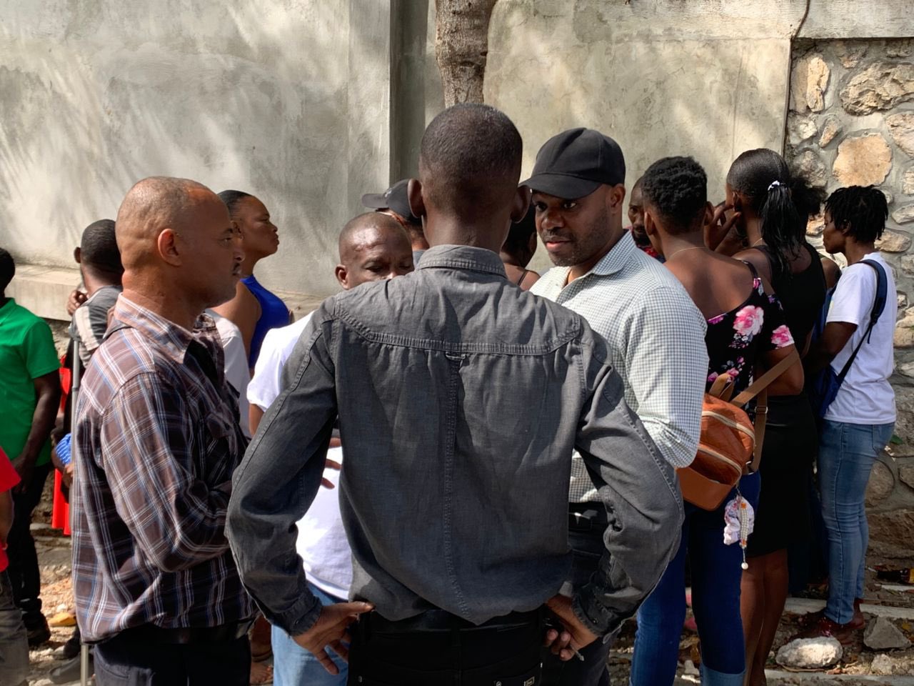 M. Herwil Gaspard porte une casquette sur la tête, en pleine conversation avec des personnes déplacées.