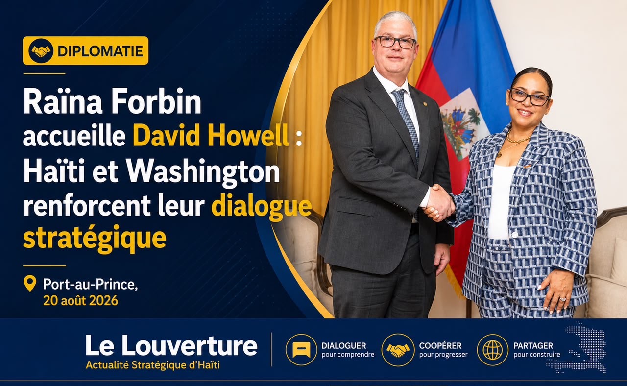 Deux responsables en costume, assis face à face dans un salon officiel, échangeant des documents devant des drapeaux haïtiens et américains.